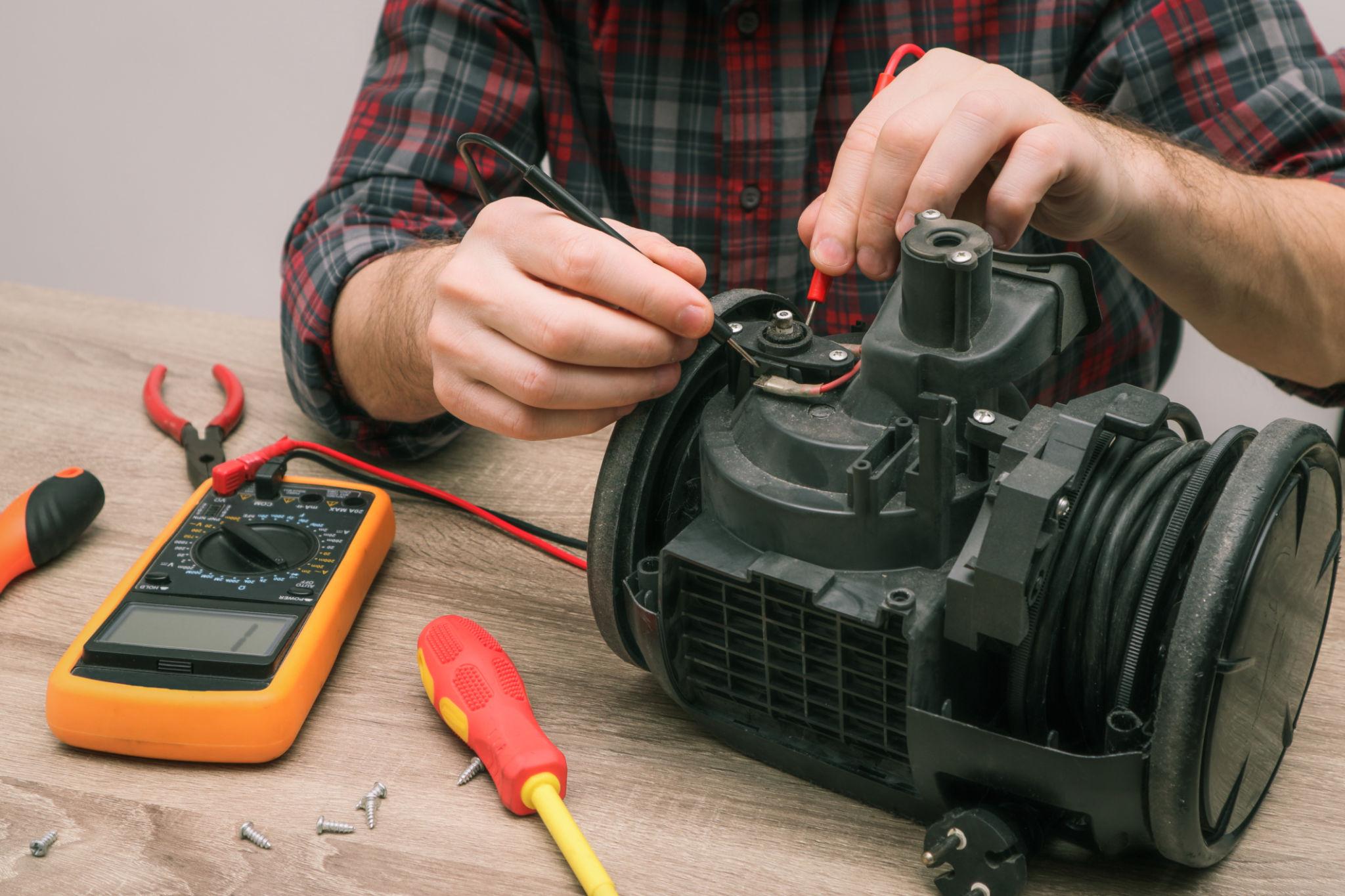 Professional technician repairing a vacuum cleaner in a workshop